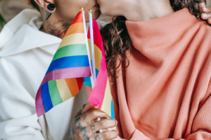 Deux personnes tenant le drapeau LGBT s'embrassant